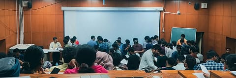 A full class at work in a coaching centre, a screen at the front.